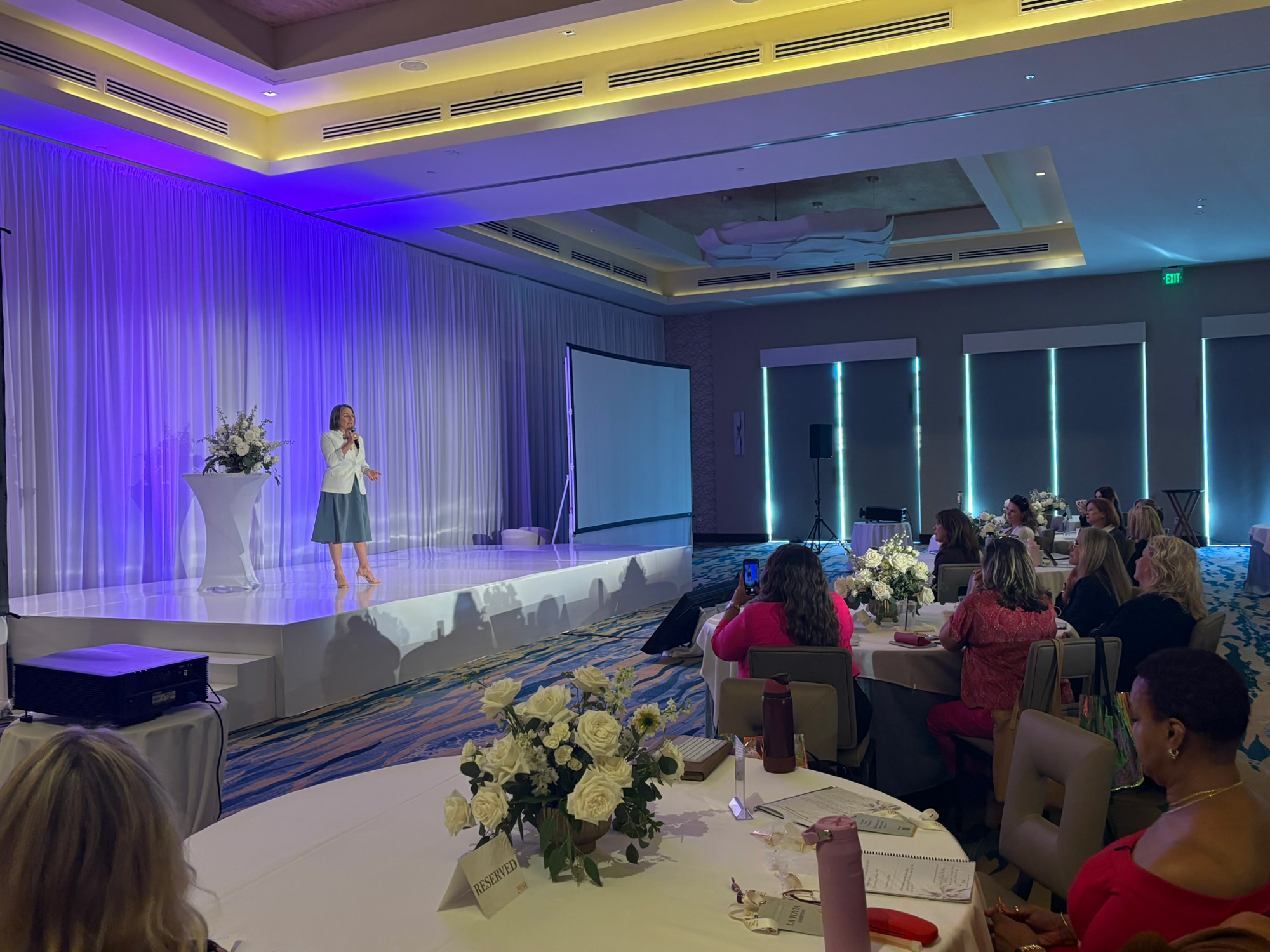 Kikki Avila on stage in a full conference ballroom